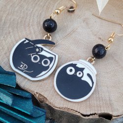 Boucles d'oreilles artisanales en émail noir avec motifs de chats dans un aquarium et perles en argile polymère pailletée.